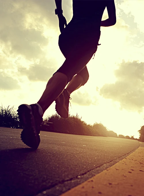Runner in motion on an open road at sunset, symbolizing fitness, endurance, and an active lifestyle.