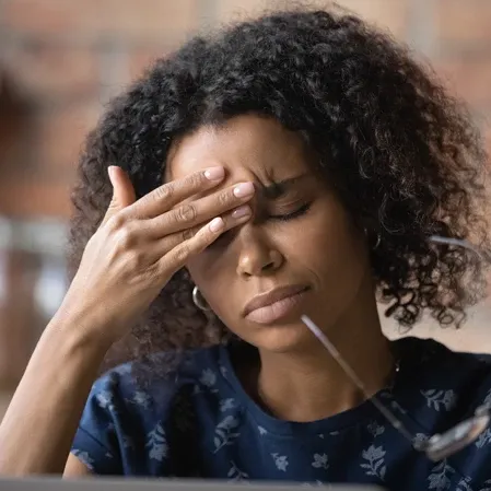 Woman pressing her forehead with eyes closed, representing stress, headache, or mental fatigue.